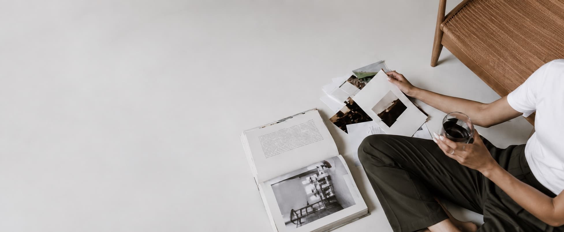 Sitting on the floor with a glass of wine, sorting photographs and an open book